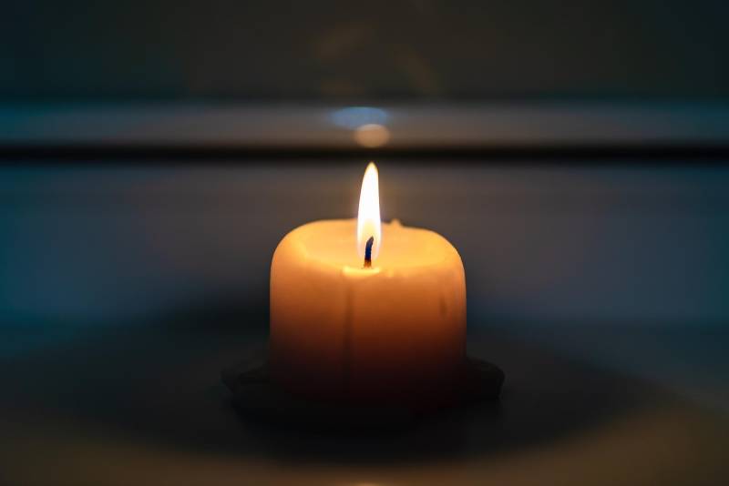 Burning candle standing on a windowsill late in the evening night